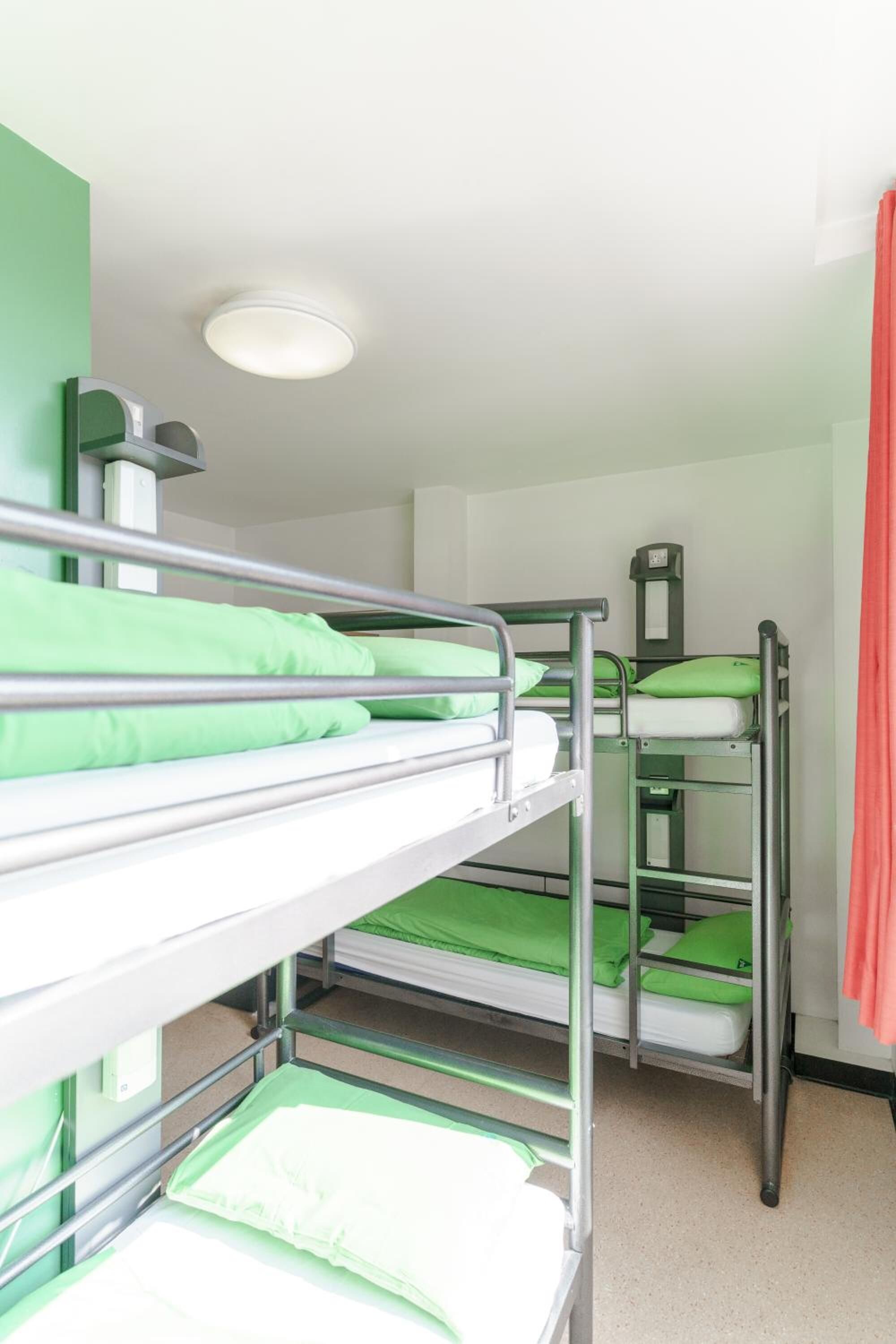 A bunk bed room with green bedding and a visible thermostat on the wall.