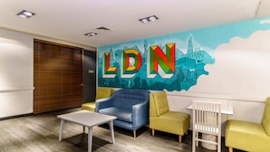 A modern waiting area with a mural, comfortable seating, and a small table. - YHA London Central - Hostel (London)