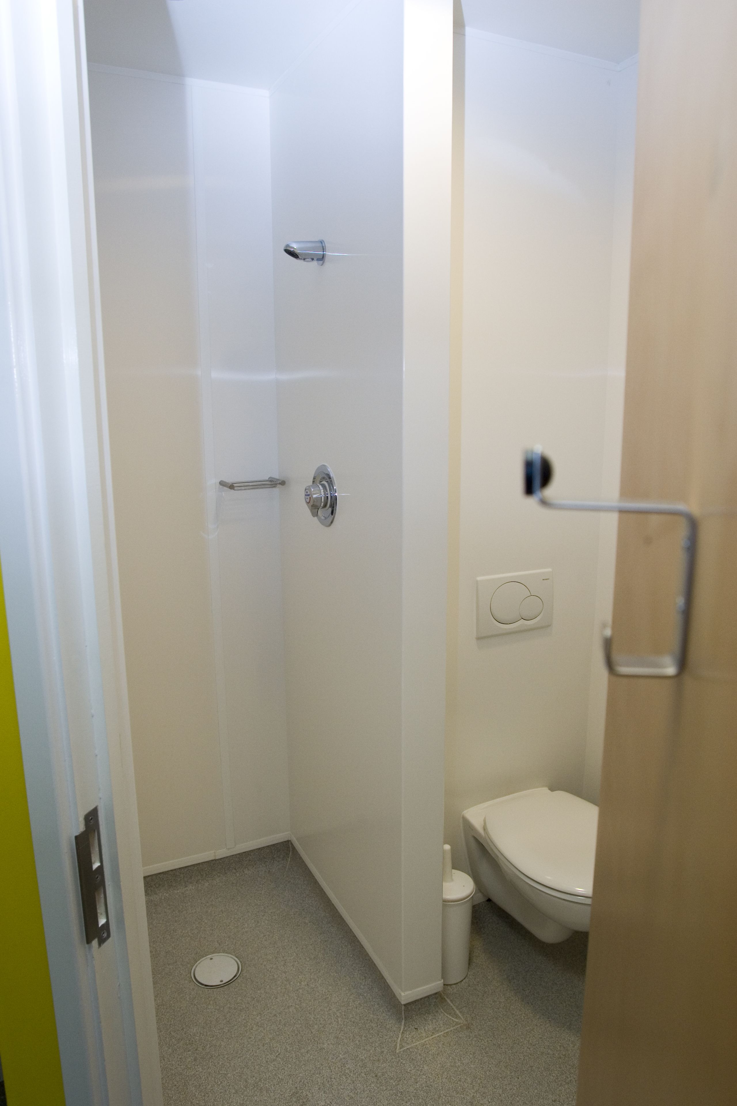A bathroom with a shower, toilet, and a towel rack.