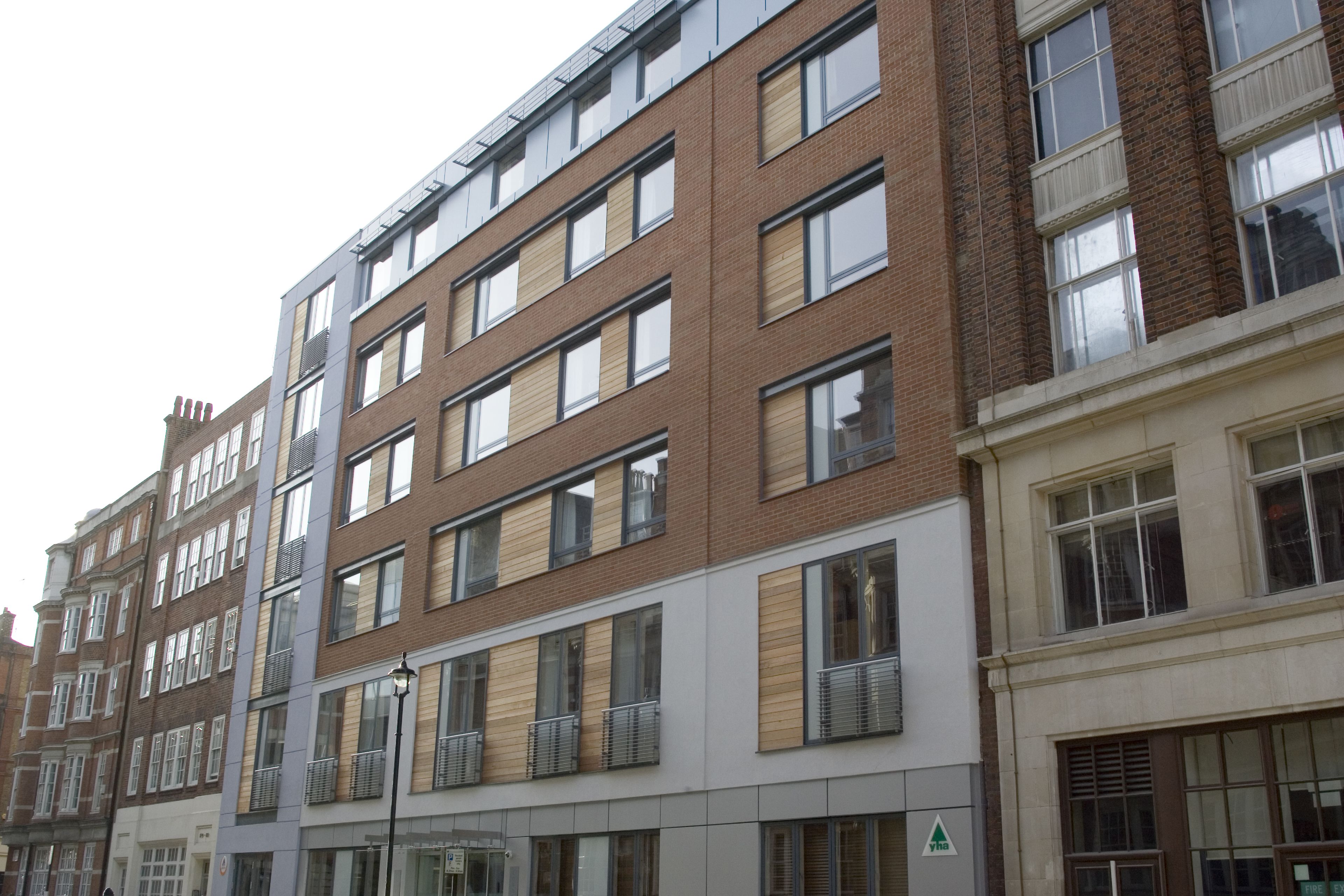 A multi-story building with a mix of brick and modern facade, featuring balconies and large windows.