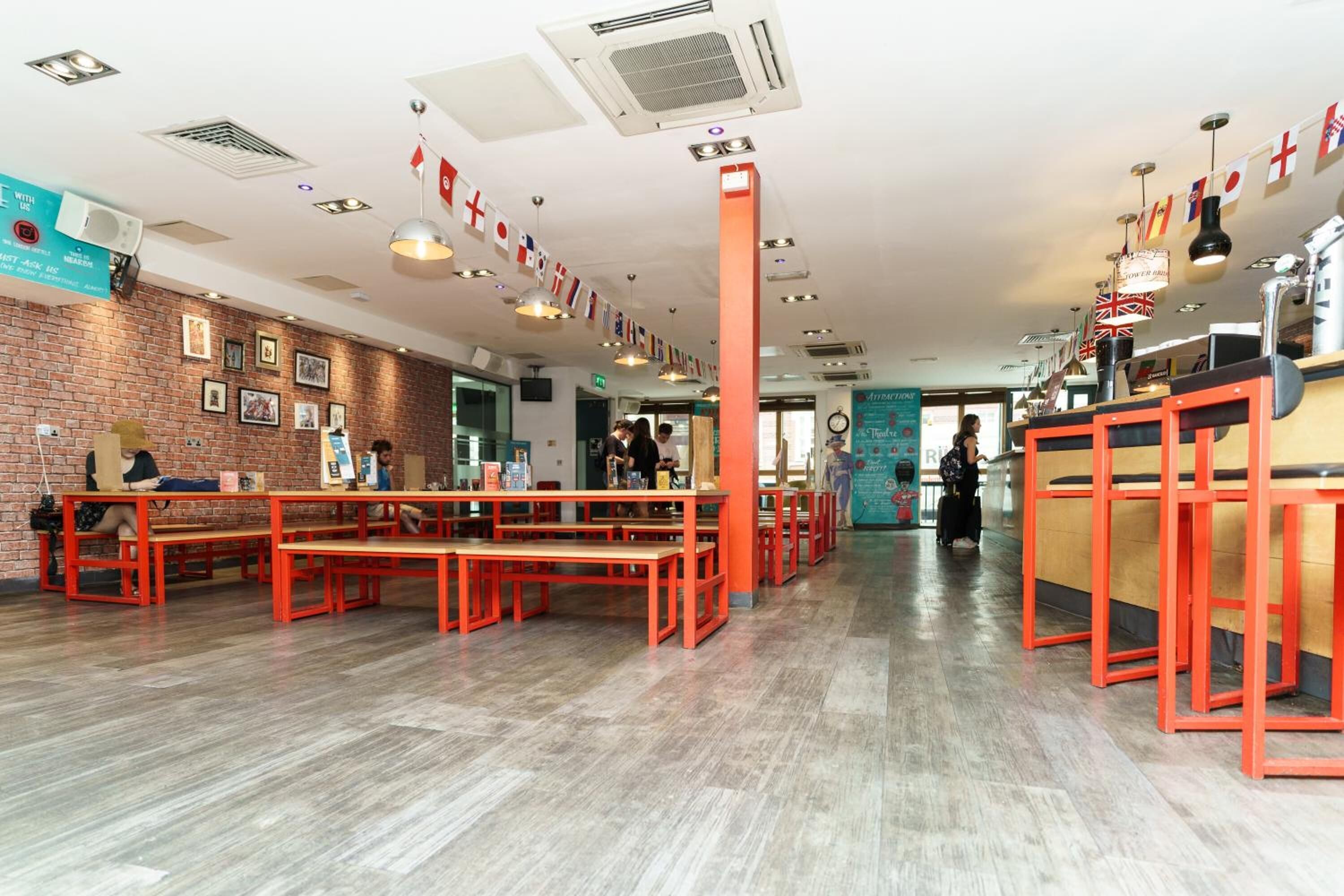 A spacious hotel lobby with red benches and a brick wall.