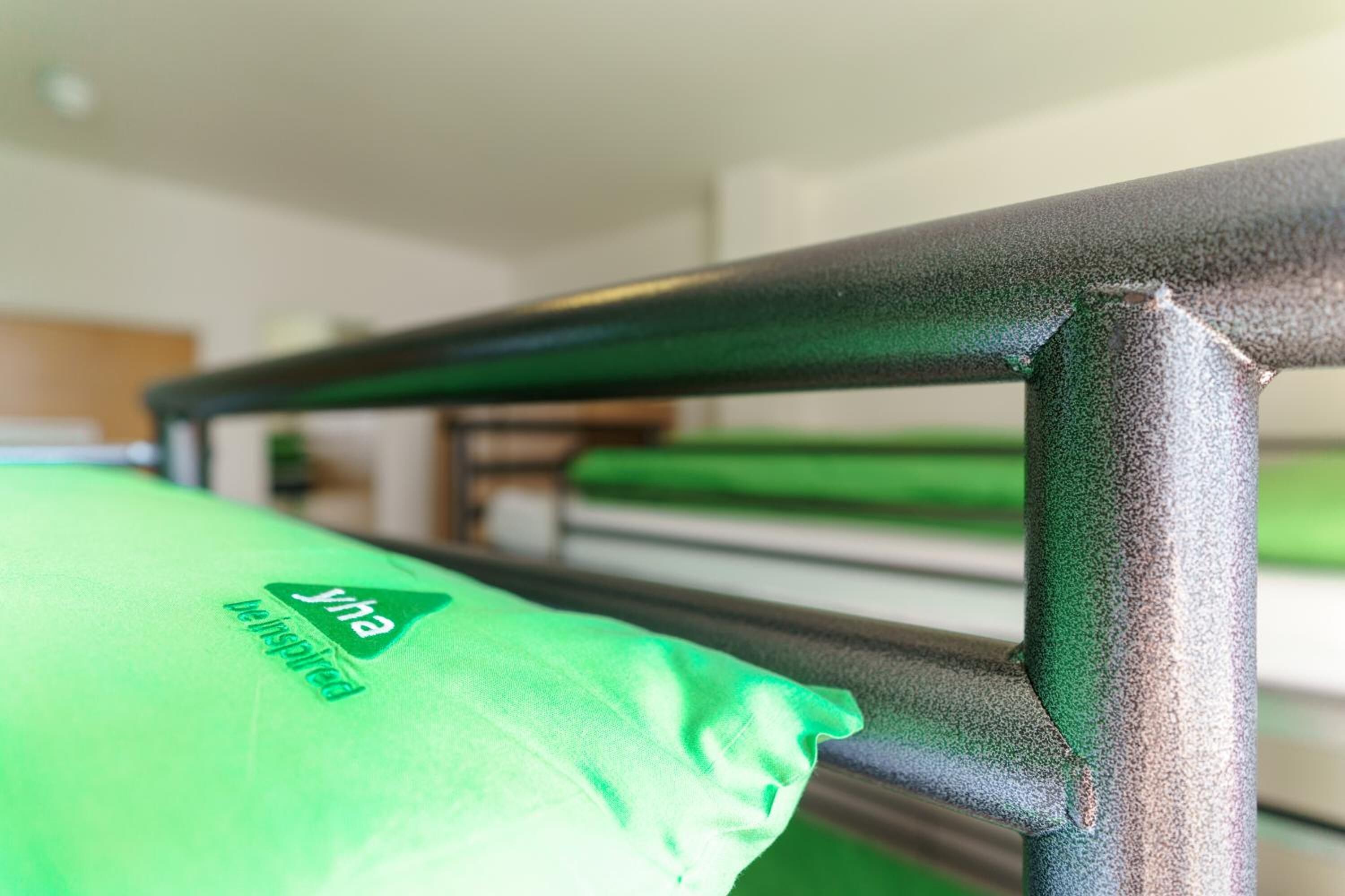 A bed with a green pillow and a metal headboard.
