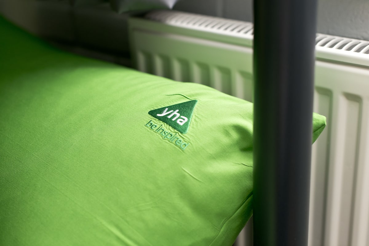 A green pillow with a logo and text on a bed.