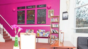 Un'area reception con una scala, una scrivania della reception, una libreria e una bacheca con informazioni sugli eventi.