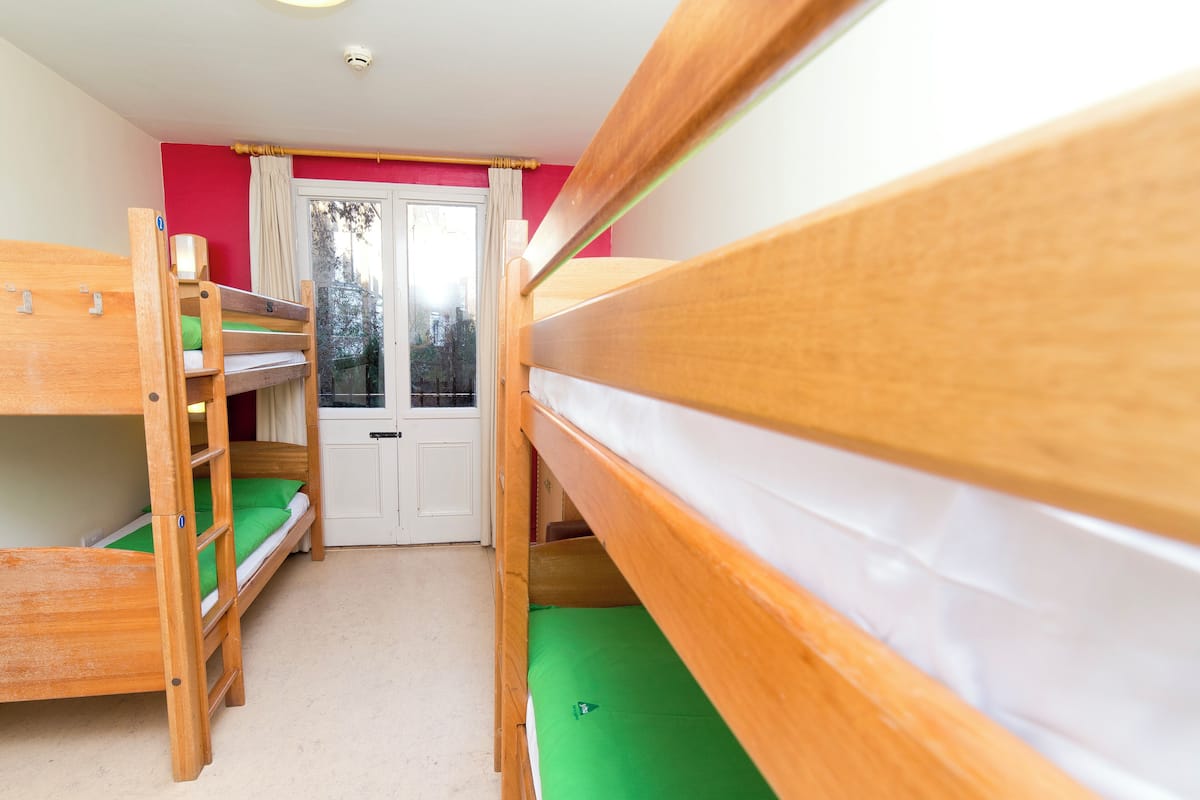 A room with bunk beds, a door, and a window.