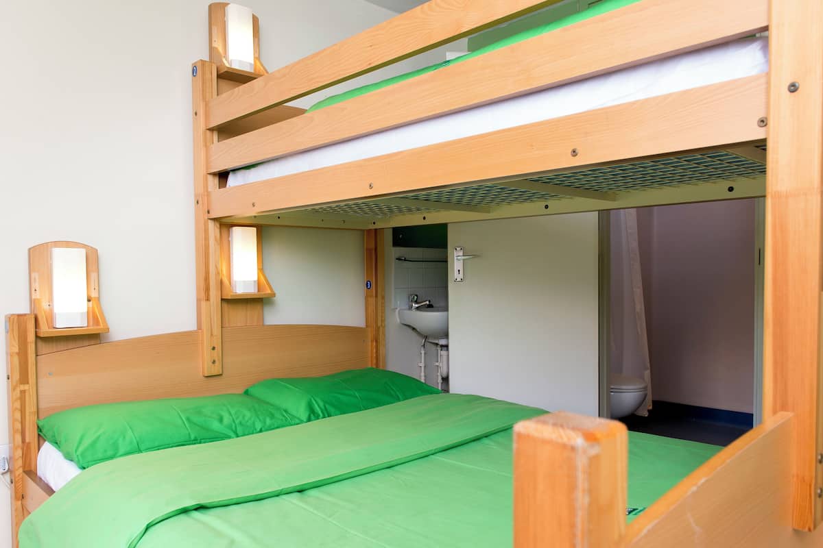 A bunk bed with a green mattress and a wooden headboard.