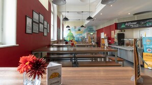 Un restaurante con mesas altas y bancos, un mural de una cúpula y un letrero que anuncia un bufé de desayuno.