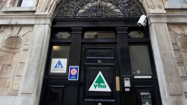 Un edificio con una puerta negra, un cartel que indica un albergue y el número 36.