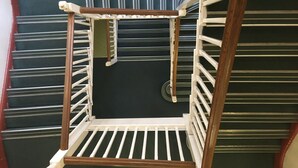 Esquina de una habitación con una silla de madera y piso negro.