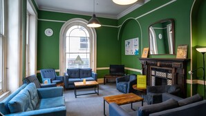 Una habitación con paredes verdes, una chimenea y varias zonas de estar, incluyendo sofás y sillones.