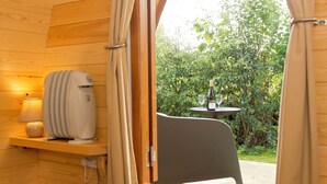 A cozy room with a wooden interior, a small table with a bottle and glasses, and a view of greenery outside. - YHA Malham - Hostel (Skipton)