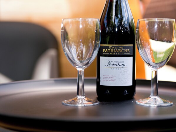 Una botella de vino Patriaire Heritage sobre una mesa con dos copas de vino vacías.