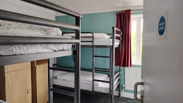 Habitación con literas, un armario de madera, un radiador y un cartel de puerta corta fuegos.