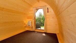 A cozy wooden cabin room with a small window, a heater, and a table with a lamp. - YHA Malham - Hostel (Skipton)