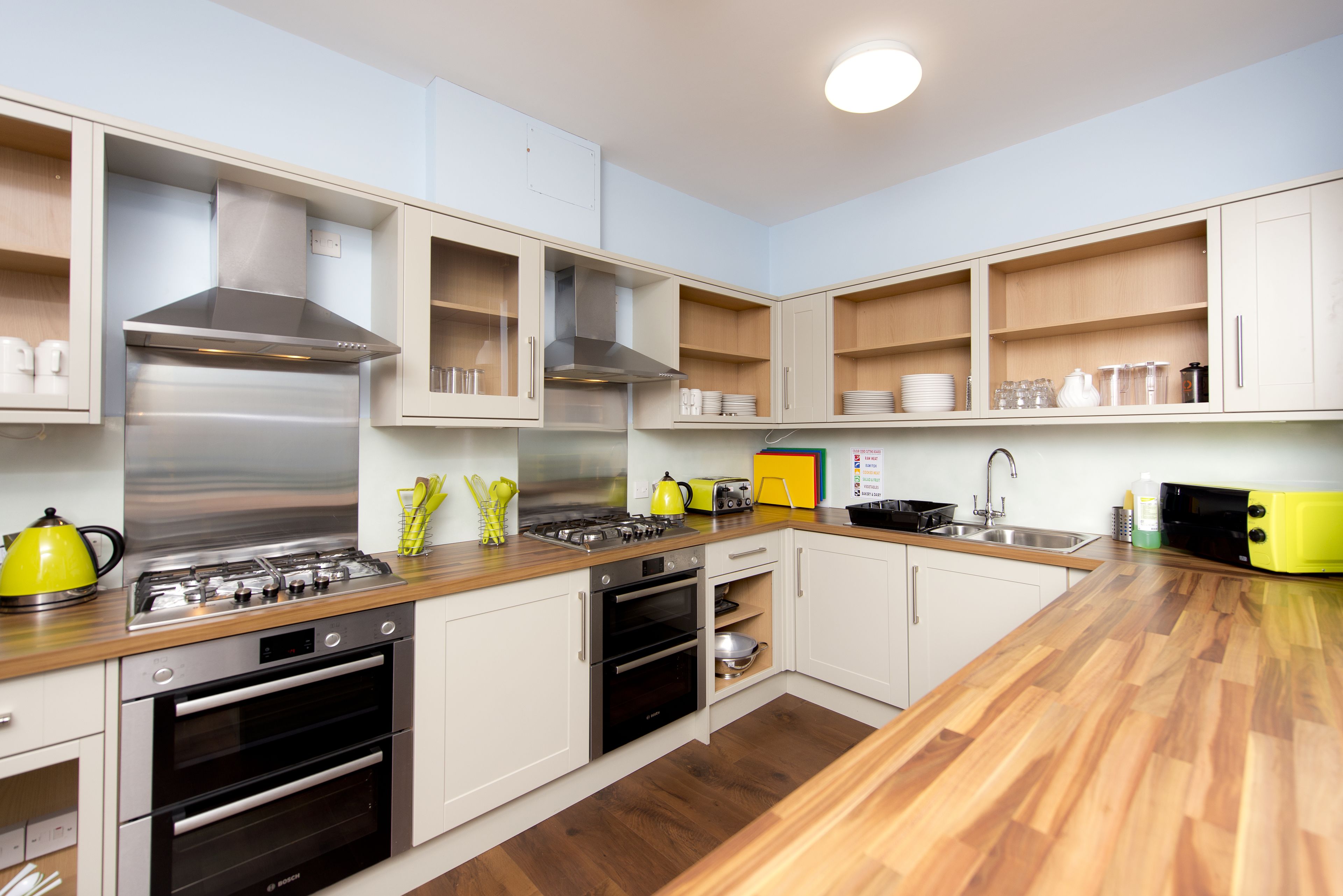 Une cuisine moderne dotée d’appareils électroménagers en acier inoxydable, de plans de travail en bois et de meubles blancs.