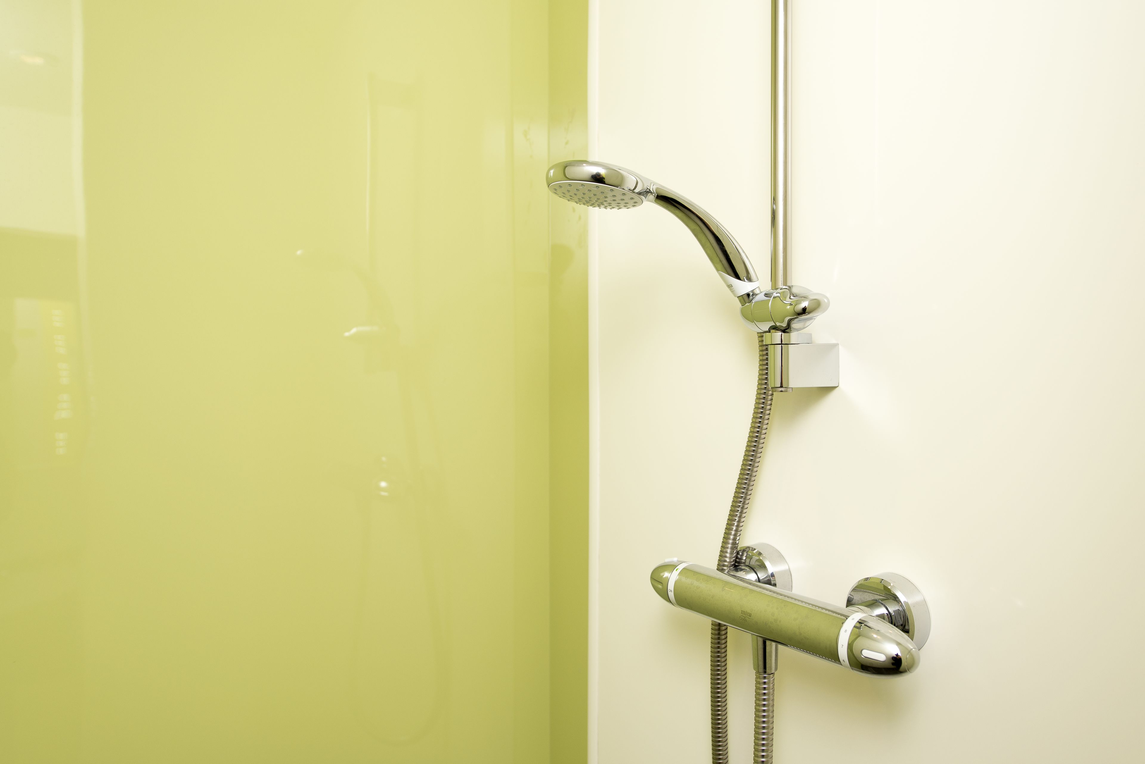 Eine Dusche mit Handbrause und Armaturen an der Wand.