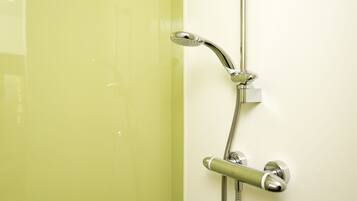 Eine Dusche mit Handbrause und Armaturen an der Wand.