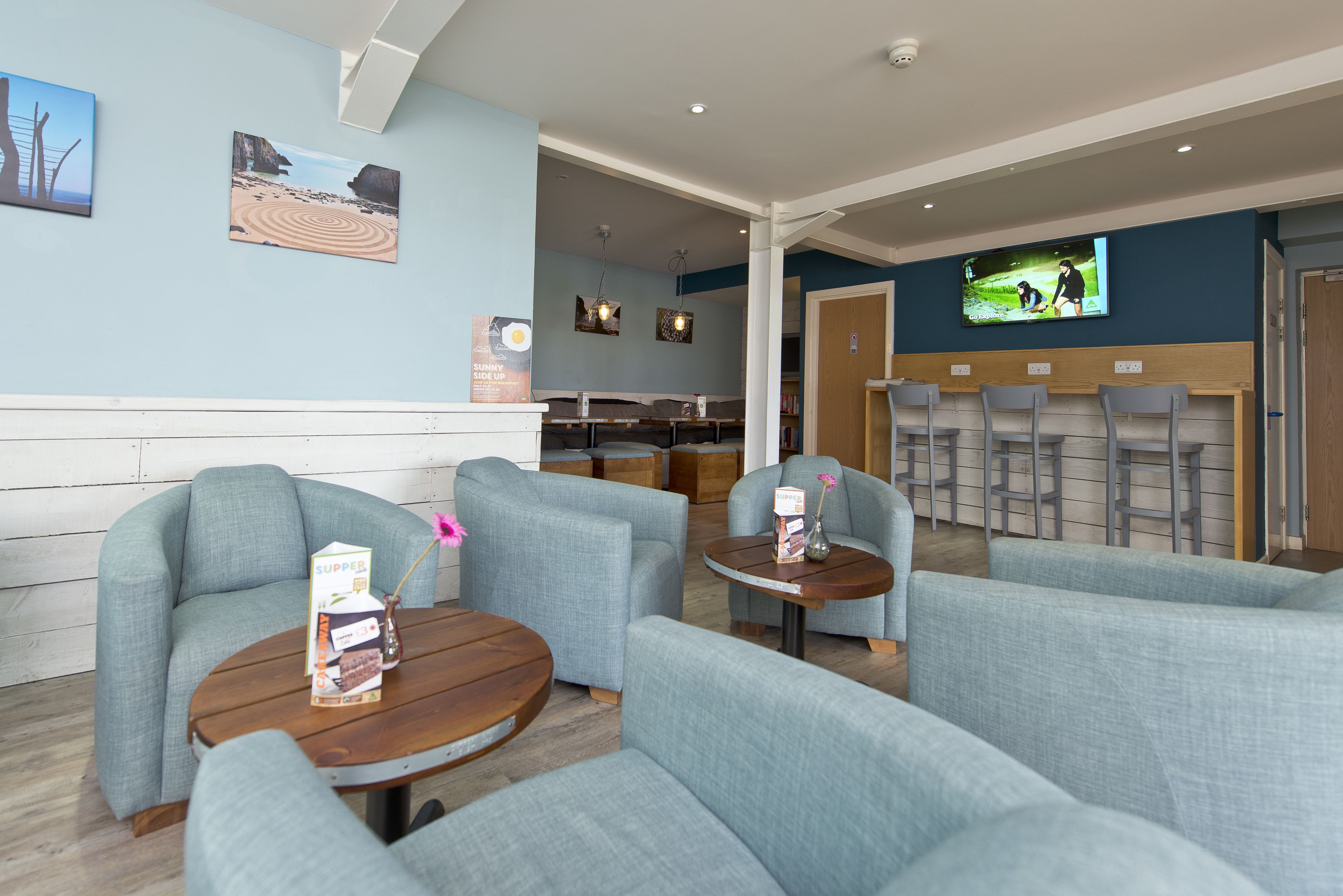 A modern lounge area with comfortable seating, a television screen, and artwork on the walls.