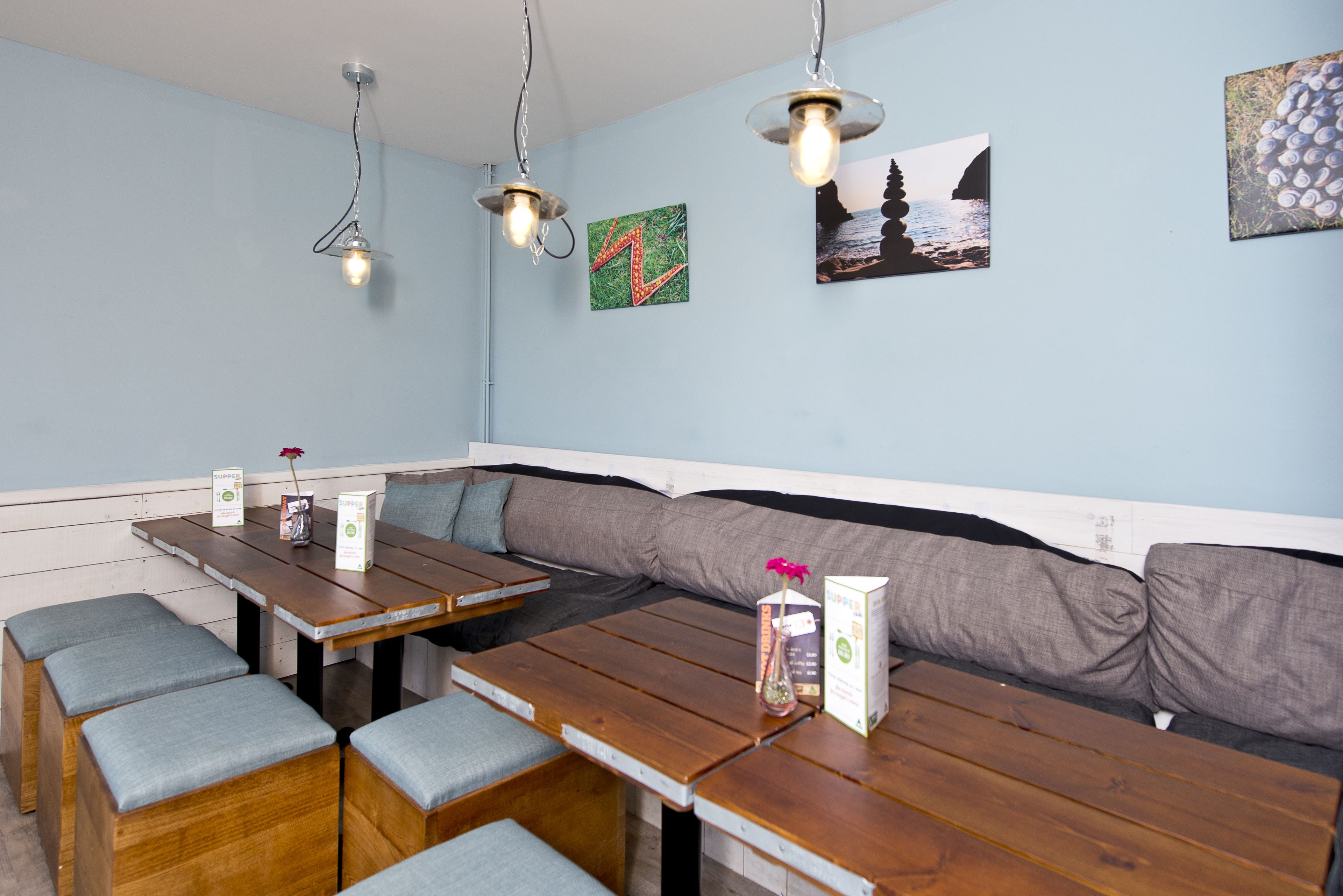 A restaurant with wooden tables and benches, a long bench seating area, and wall art.