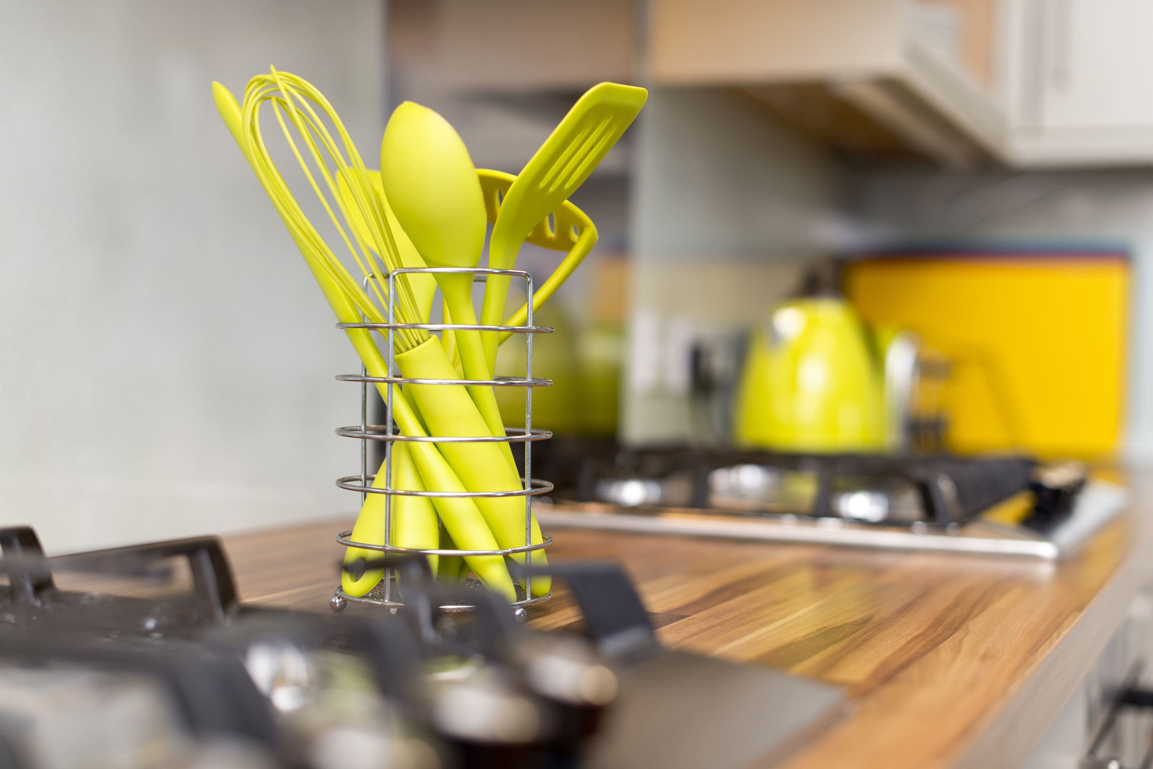 Una encimera de cocina con un portalapices que contiene utensilios amarillos.