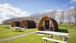 A campsite with wooden cabins and picnic tables.