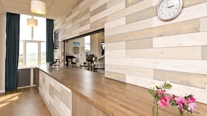 A reception area with a wooden panel wall, a clock, and a counter with a menu board.