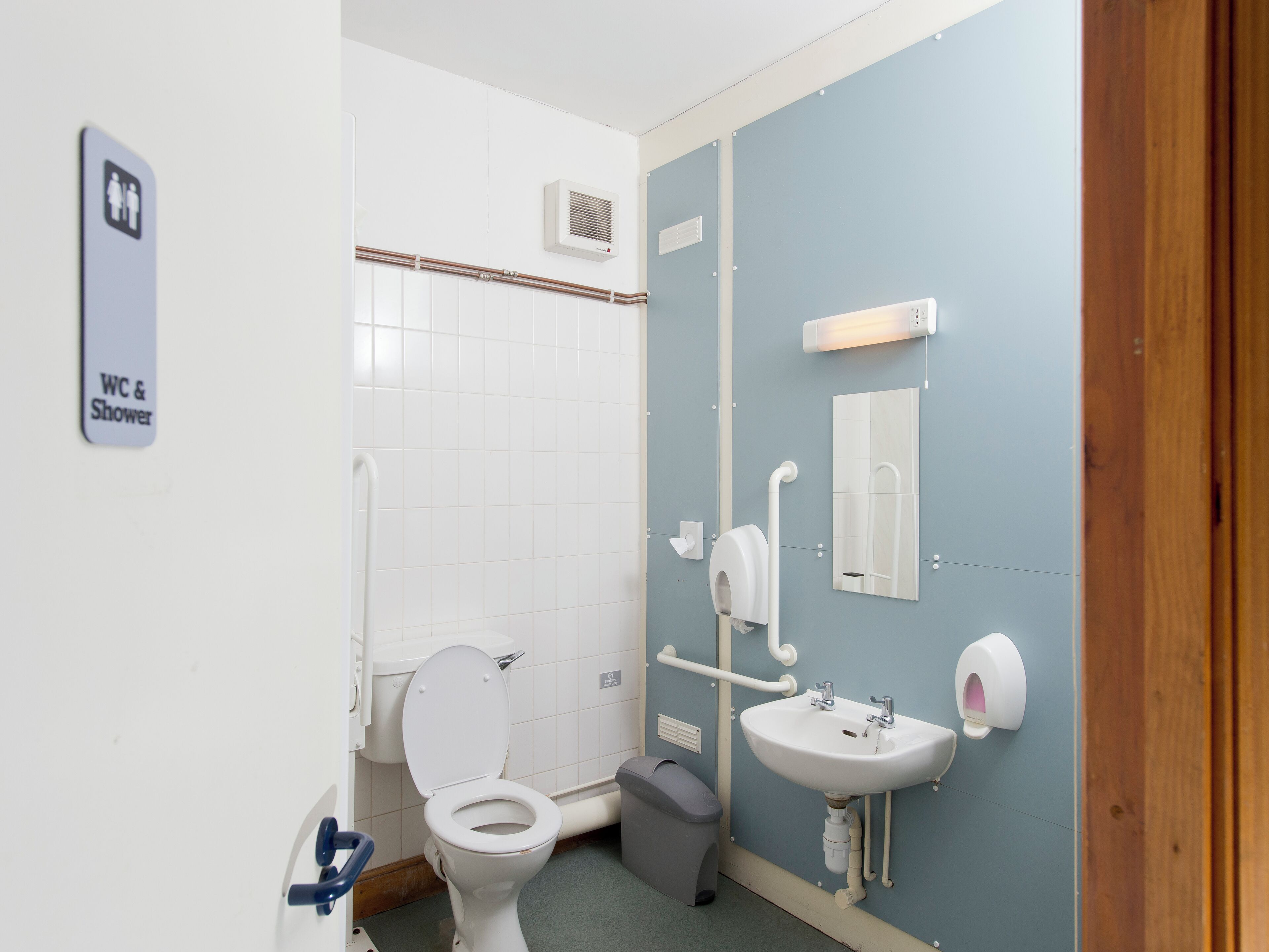 Un baño con inodoro, lavamanos y secamanos.