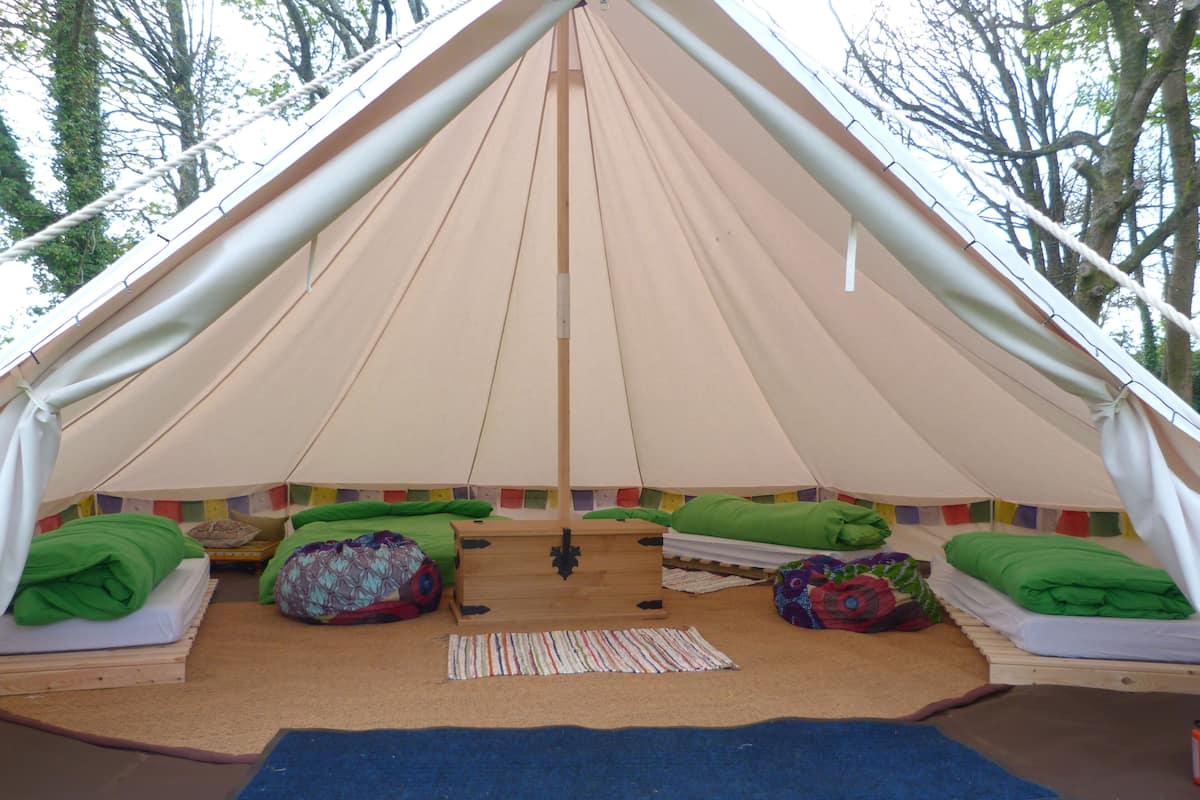 Una carpa con dos camas, una mesa en el centro y un tapete en el suelo.