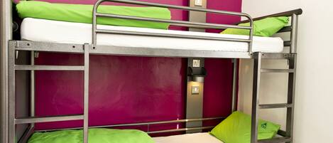 A bunk bed with green bedding and a wall-mounted light fixture.