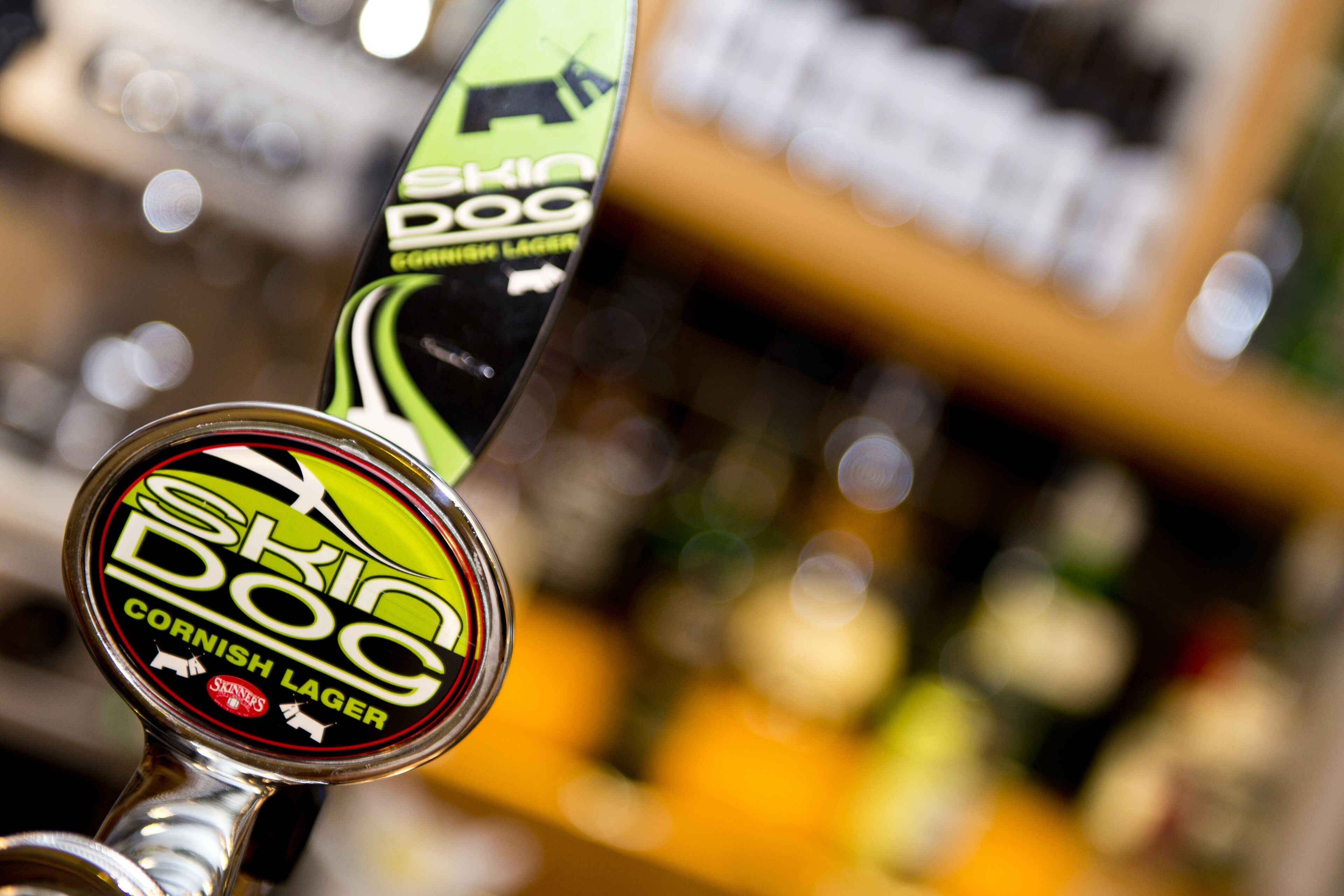 A beer tap labeled "Skid Dog Cornish Lager" with a green and black design.