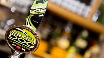A beer tap labeled "Skid Dog Cornish Lager" with a green and black design.