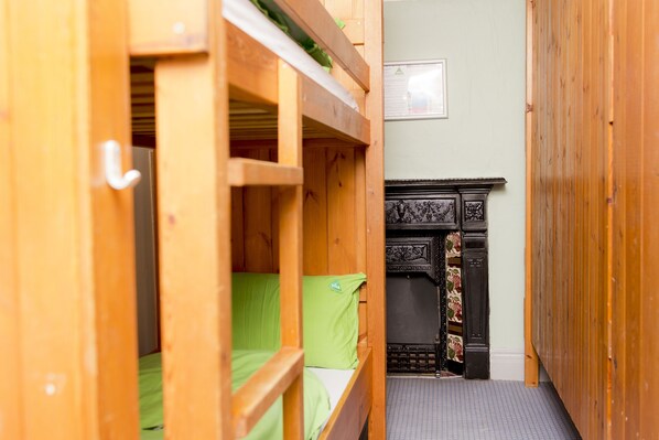 A wooden bunk bed room with a fireplace and a framed notice on the wall.