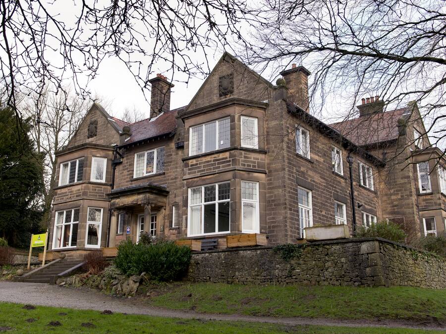 A large, historic stone building with multiple windows and a prominent entrance.