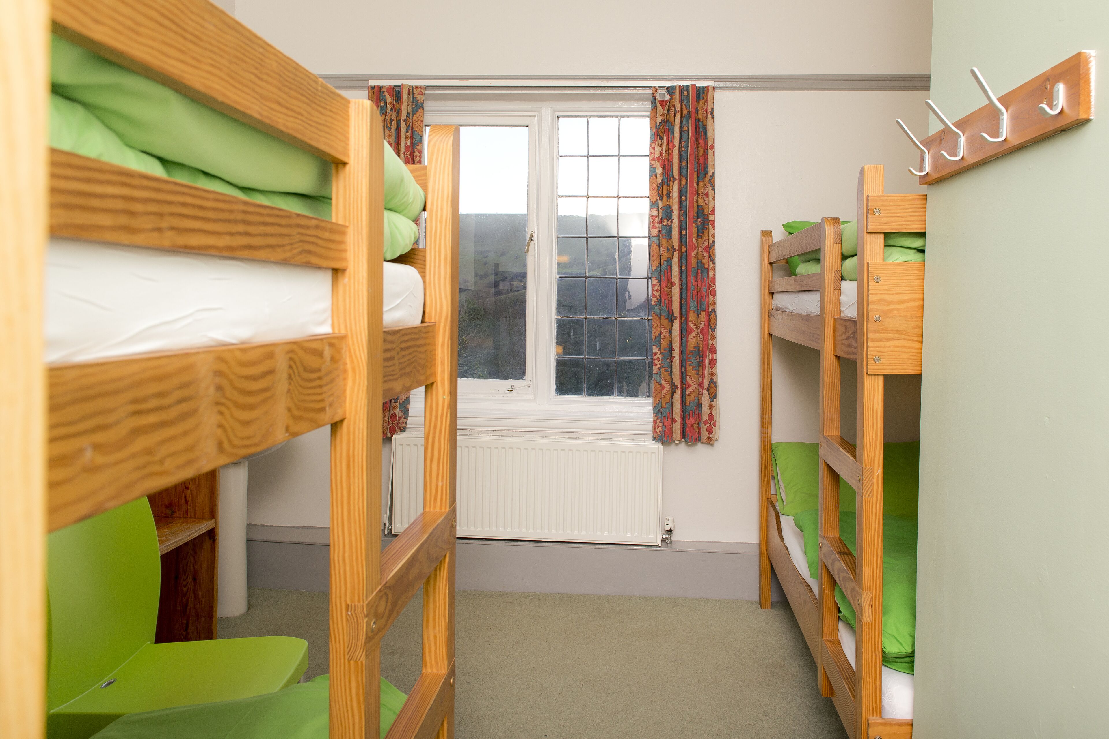 A room with bunk beds, a window with curtains, and a radiator.