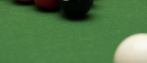 A pool table with billiard balls in red, yellow, and black colors.