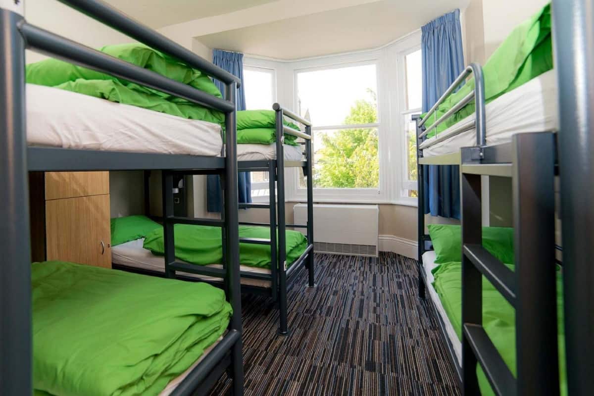 Un dormitorio con literas, una ventana y un radiador.
