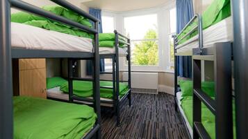 Un dormitorio con literas, una ventana y un radiador.