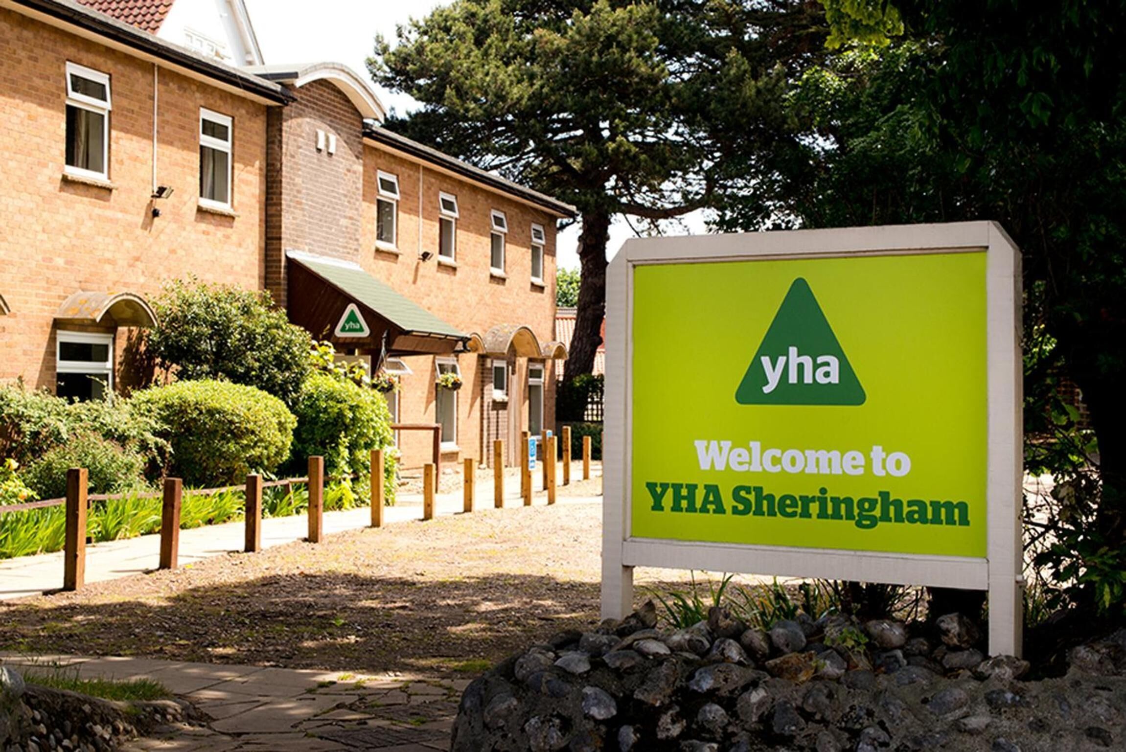 A sign welcoming visitors to YHA Sheringham, indicating the presence of a hotel or accommodation facility.
