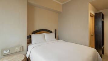 Una cama bien hecha con sábanas blancas en una habitación de hotel.