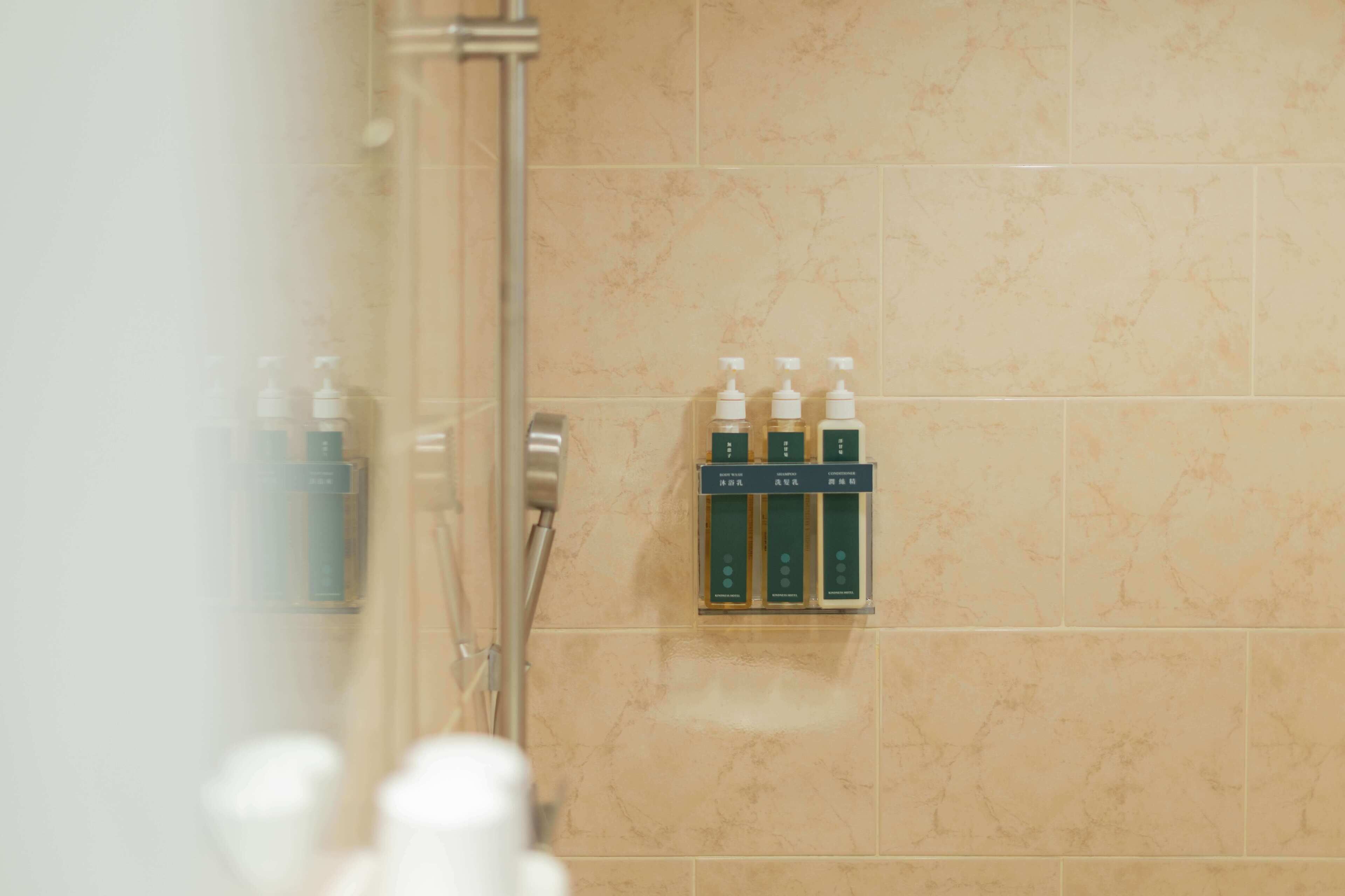 A bathroom with a wall-mounted dispenser holding three bottles of toiletries.
