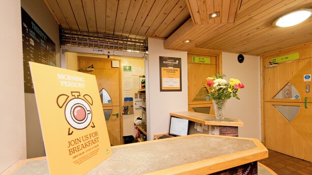 Et receptionområde med en træreception, et skilt der reklamerer for morgenmad, og et loungeskilt.