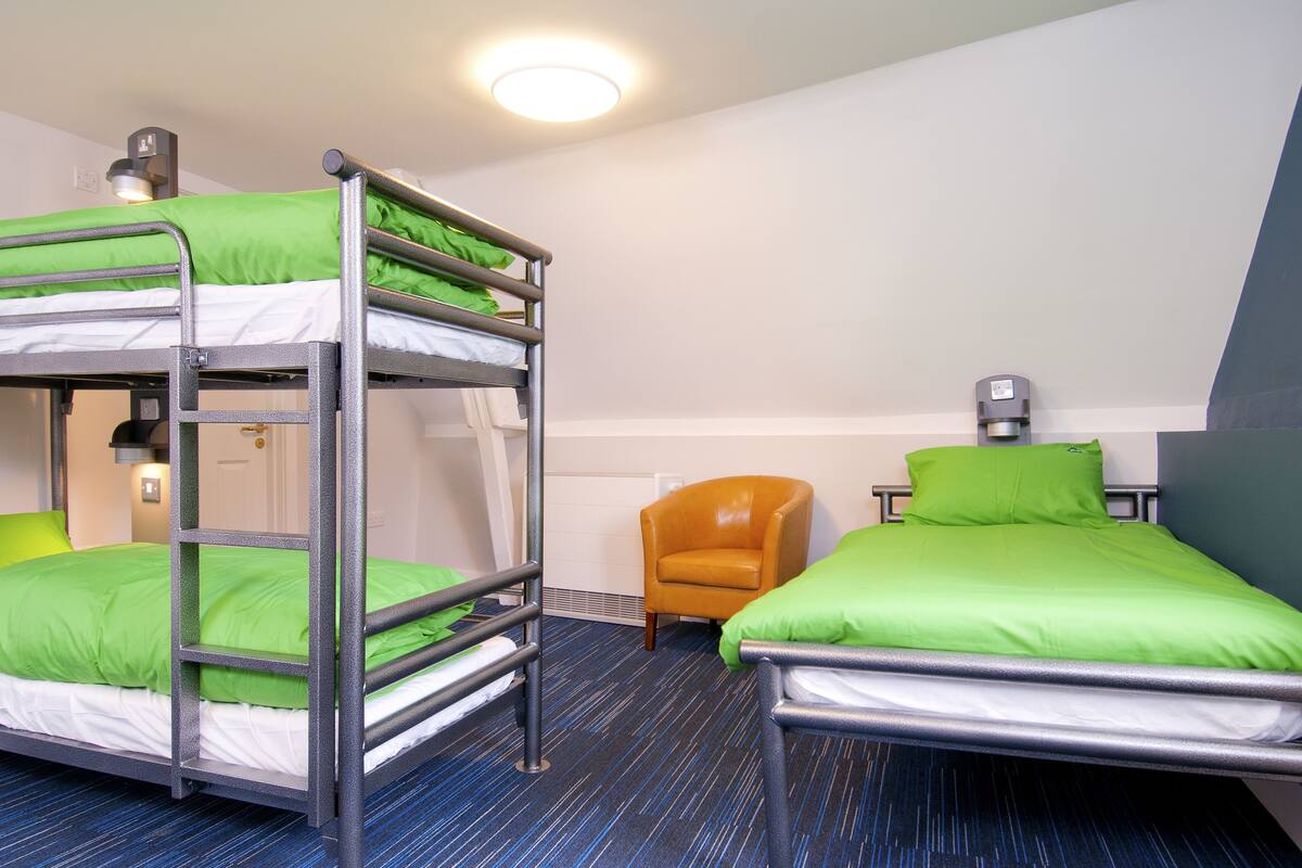 A room with bunk beds, a chair, and a desk.