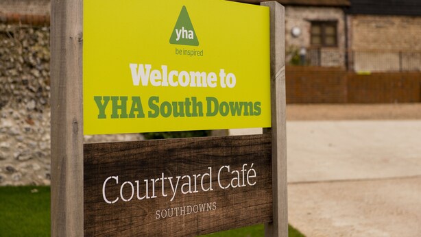 A sign welcoming visitors to YHA South Downs, indicating the location of the Courtyard Café. - YHA South Downs - Hostel (Lewes)