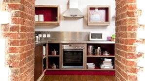 A kitchen with a brick archway, stainless steel appliances, and wooden shelves. - YHA South Downs - Hostel (Lewes)