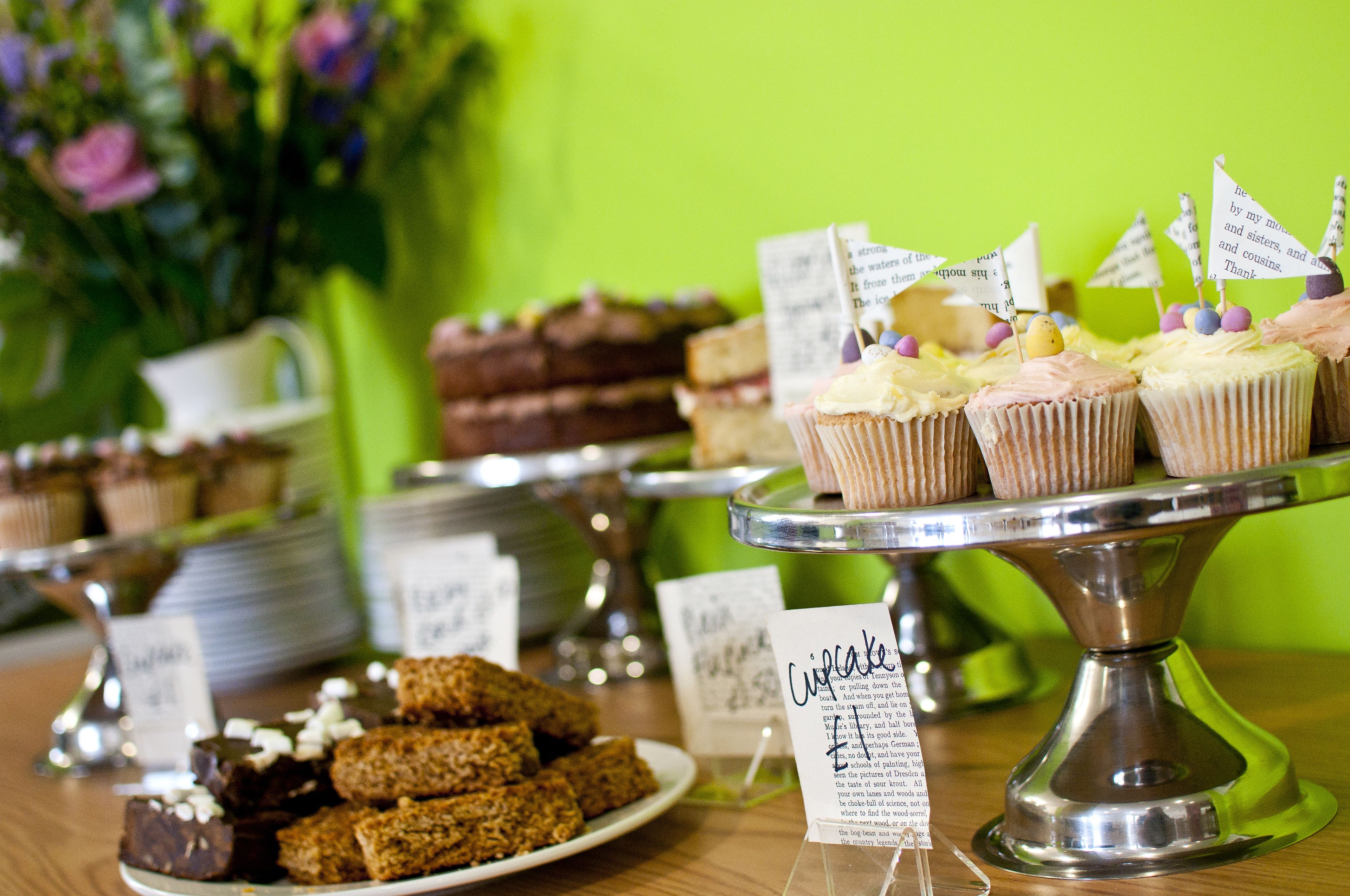 Se exhibe una variedad de postres, entre ellos cupcakes y brownies, con etiquetas que indican sus nombres.