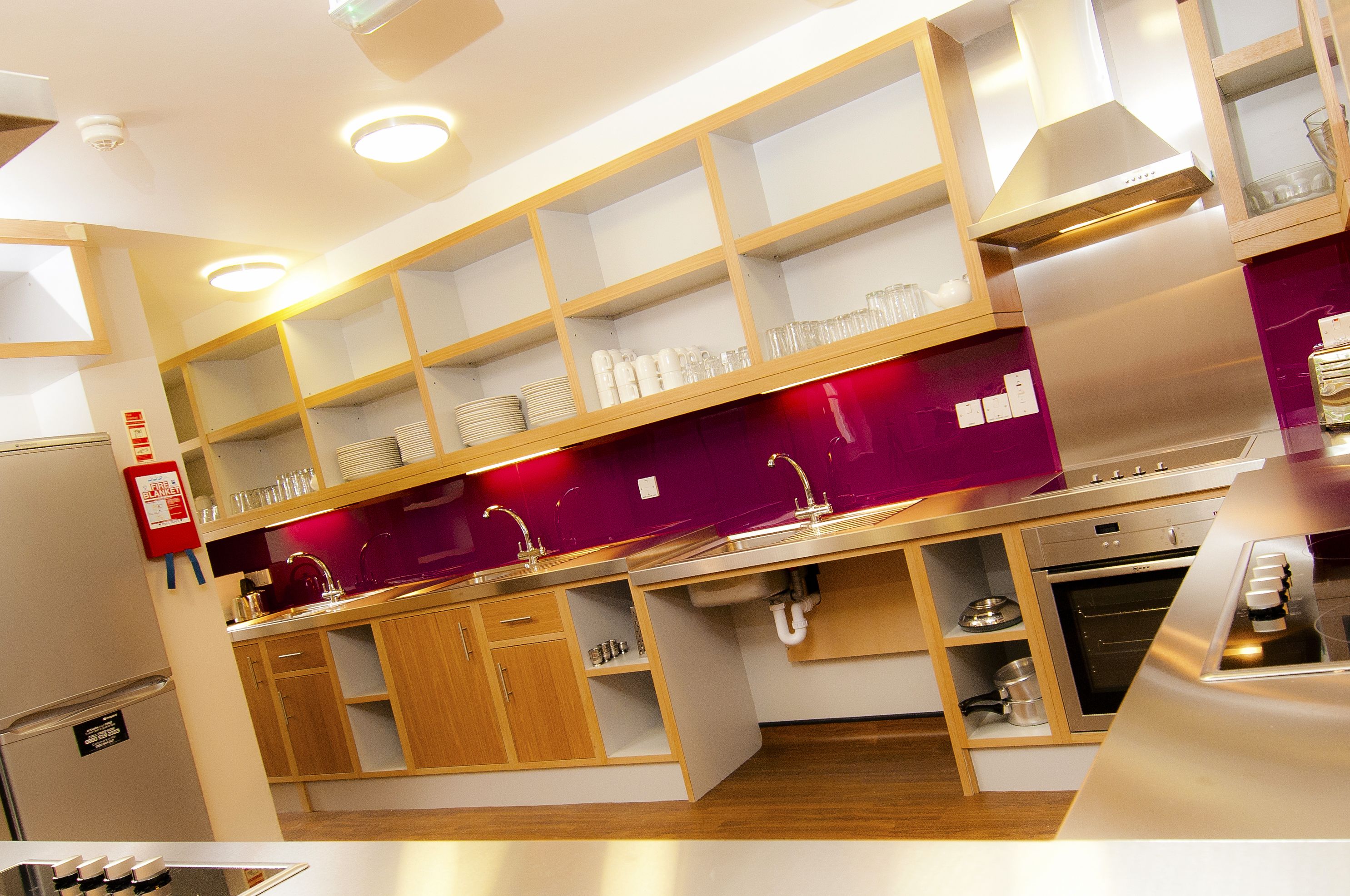 Una cocina moderna con armarios de madera, electrodomésticos de acero inoxidable y estanterías empotradas.