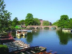 Un río con barcos amarrados a la izquierda y un puente al fondo.
