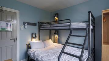 A bunk bed room with a door, a nightstand, a wall-mounted light, and a wooden cabinet.