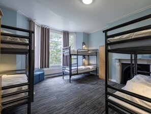 A dormitory room with bunk beds, a radiator, a window with curtains, and a small cabinet. - YHA Stratford-upon-Avon - Hostel (Stratford-upon-Avon)