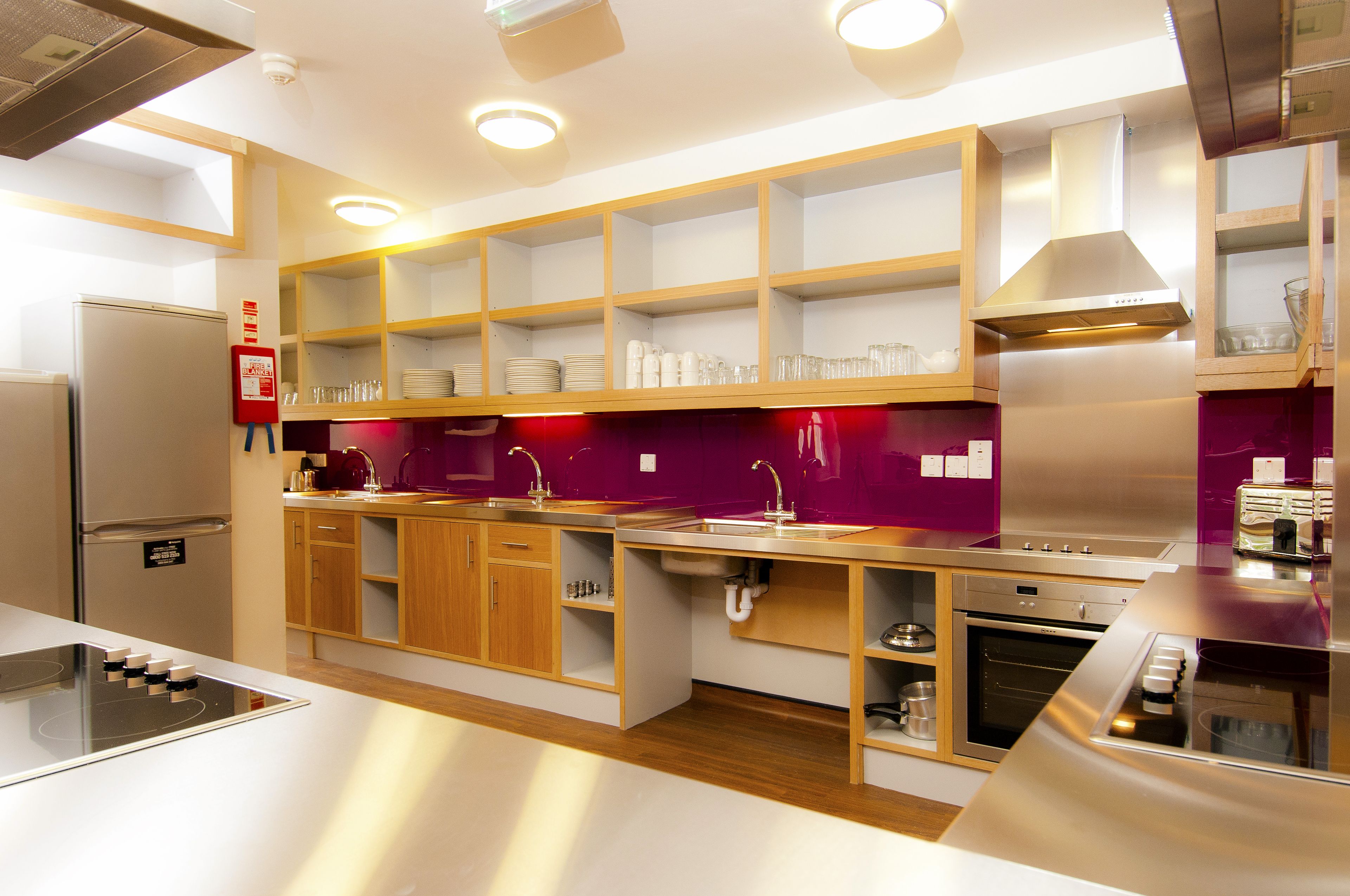 A modern kitchen with built-in appliances, wooden cabinets, and a purple backsplash.